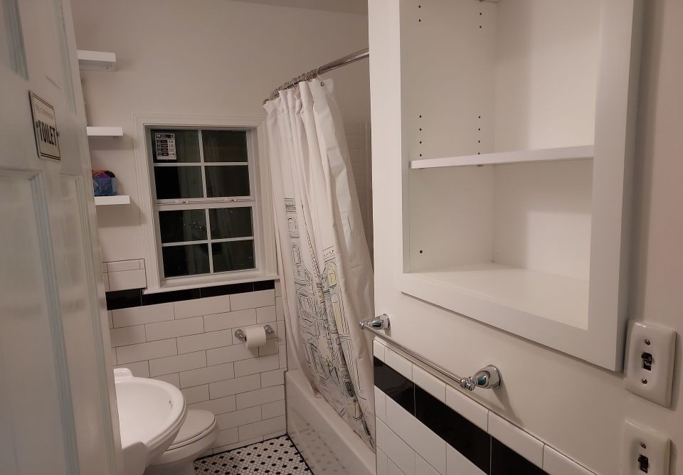 Bathroom after remodel — white subway tile, black accent tile, and hex floor