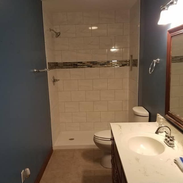 Completed bathroom remodel with tiled walk-in shower and accent tile band